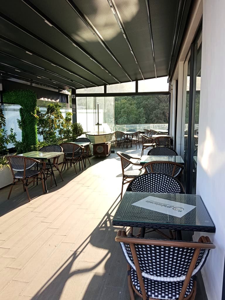 Terrasse-restaurant de l'Hôtel Printania sous verrière, tables et chaises bistrot